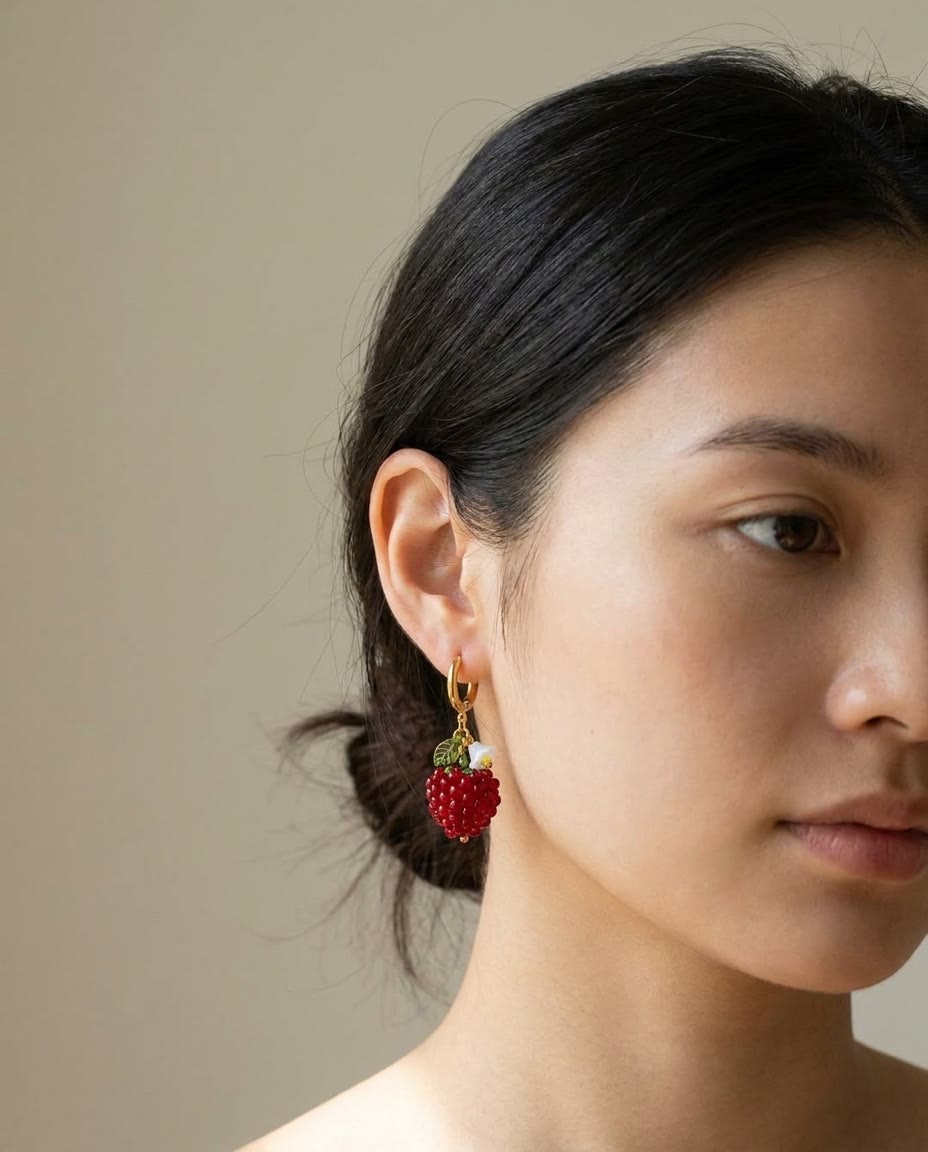 Beaded raspberry earring worn by a model against a warm studio backdrop