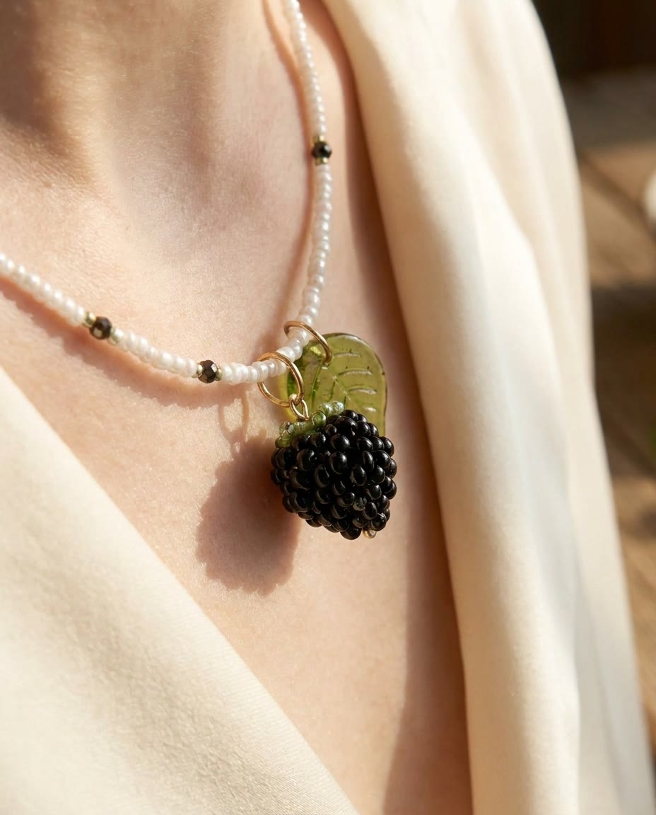 Blackberry pendant on a pearl necklace worn over cream silk